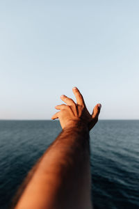 Cropped hand of woman gesturing against clear sky