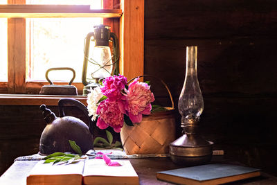 Still life of vintage items and a bouquet of peonies on a table by the window in village house