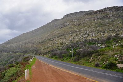 Road leading towards mountains against sky