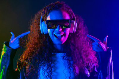 Portrait of woman wearing sunglasses while standing against black background