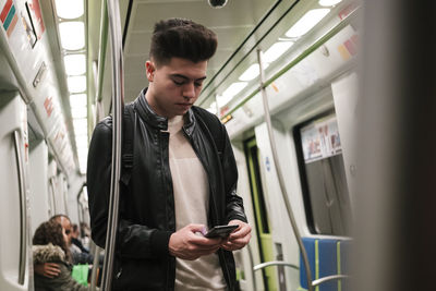 Young man using smart phone in subway train