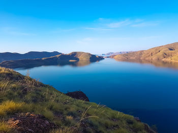 Scenic view of lake and mountains against blue sky