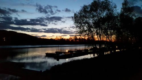 Silhouette of boats in lake at sunset