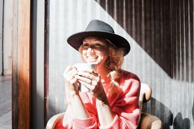 Woman smiling whilst drinking coffee in the sunshine in a cafe in fall