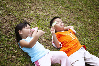 Friends eating candies while lying on field at park