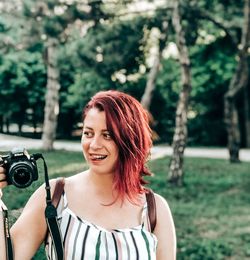 Portrait of smiling young woman standing against trees