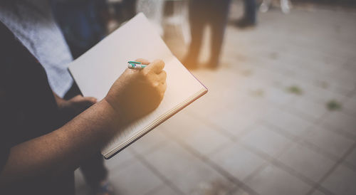 Midsection of woman writing in diary