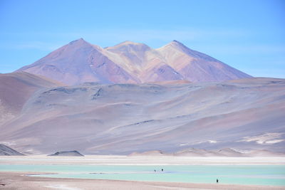 Scenic view of sea by mountains against sky