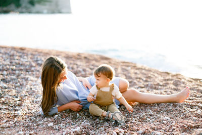 Rear view of women sitting on pebbles at beach