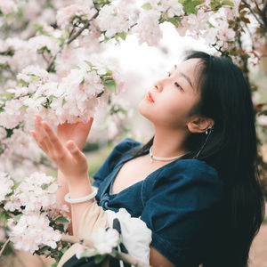 Side view of young woman blowing flowers