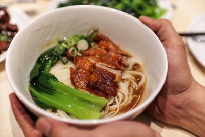 Close-up of hand holding bowl of food