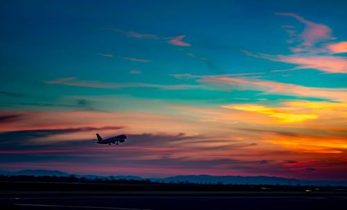 Silhouette airplane flying against sky during sunset