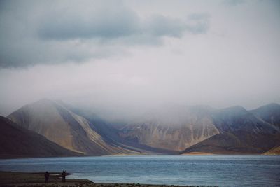 Scenic view of sea by mountains against sky
