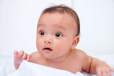 Close-up of naked baby boy lying on bed