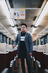 Full length portrait of young man standing on seat