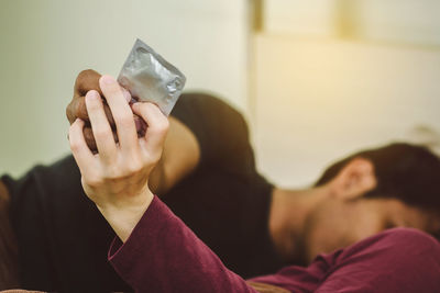 Close-up up couple holding condom lying on bed at home