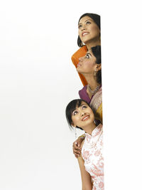 Female friends smiling by wall against white background