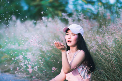 Beautiful young woman standing by pink flower tree