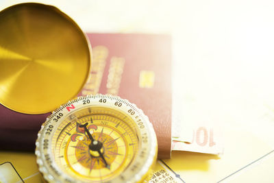 Close-up of navigational compass with passport and money on table