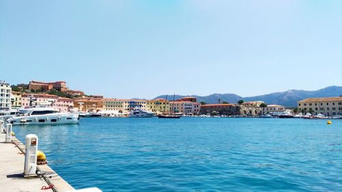 Boats on sea by buildings against blue sky