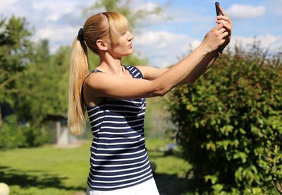 Woman taking selfie while standing against sky