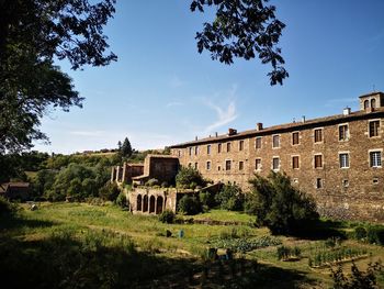 Old building by trees against sky