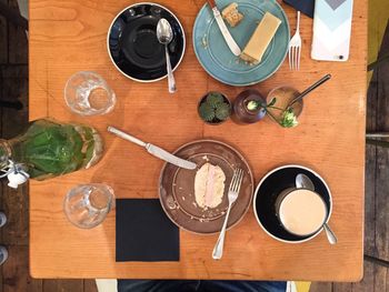 High angle view of cake in plate and coffee cup on wooden table