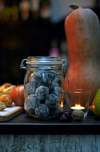 Close-up of fruits in jar by lit tea light on table
