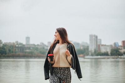 Young woman standing against river