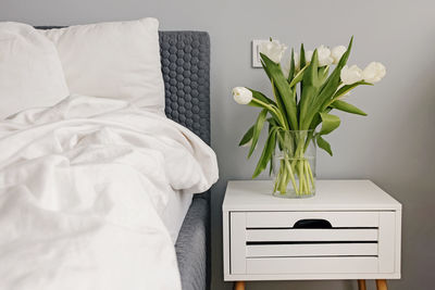 Low section of woman with flowers on bed at home