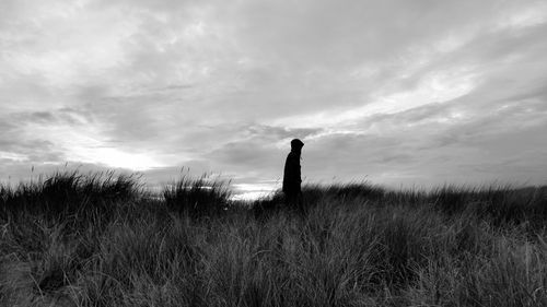 Silhouette man standing on field against sky