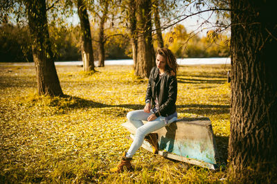 Young woman sitting on abandoned boat at forest