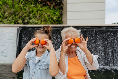 Happy grandmother and granddaughter playing with mandarins
