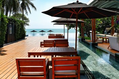 Empty chairs and tables in resort on sunny day