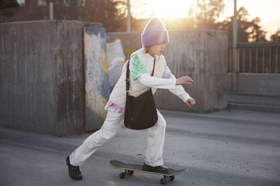 View of girl skateboarding, sunset shining in background