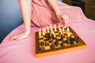 Midsection of woman dressed in pink playing chess 