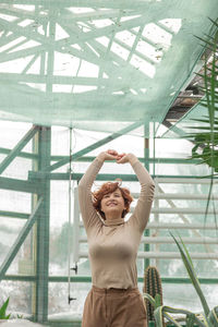 A beautiful plus size girl enjoying standing among the green plants of the greenhouse. 