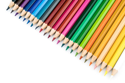 High angle view of colored pencils on white background