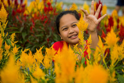 Smiling girl touching yellow flowers at park