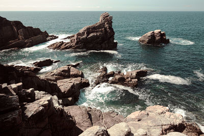 Scenic view of rocks in sea against sky