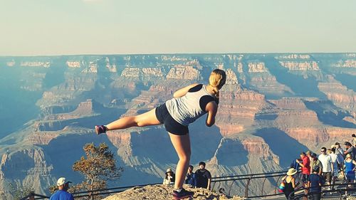 Rear view of woman standing on leg in front of people at grand canyon national park