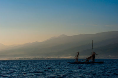 Sailboat in sea against sky during sunset