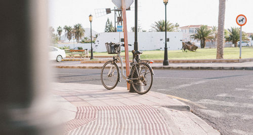 Bicycle parked on sidewalk by road in city