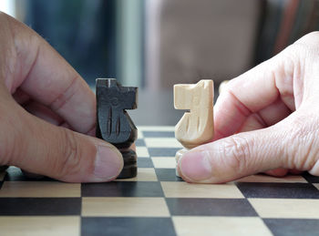 Cropped hands of person holding knights on chess board 