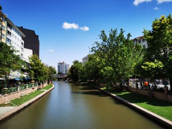 Canal amidst trees and buildings against sky