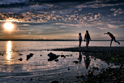People on beach against sky during sunset