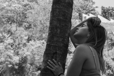 Young woman standing by tree at park