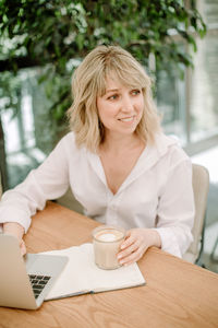 Portrait of young woman with coffee cup on table