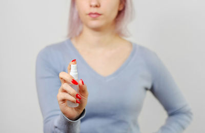 Midsection of woman holding while standing against white background