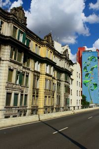 Road by buildings in city against sky